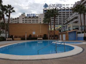 une grande piscine avec un hôtel en arrière-plan dans l'établissement Apartamento bahia park 1a linea Marina d'or, à Oropesa del Mar