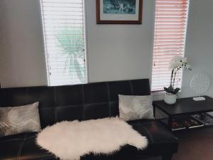 a black leather couch with a white furry rug at The Heart of Rotorua in Rotorua