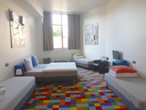 a living room with three beds and a colorful rug at FunKey Hotel in Brussels
