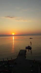 a sunset over a body of water with people on a dock at Eros Beach Hotel in Benitses