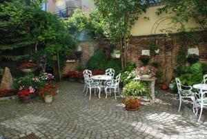 a patio with white chairs and tables and flowers at Appartements Andrea in Klosterneuburg