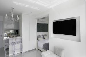 a white bedroom with a bed and a flat screen tv at The White Pearl Suite - beach front city centre with sea view. in Limassol