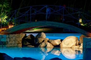 a bridge over a pool with rocks in the water at Camping villaggio L'Ultima spiaggia in Bari Sardo