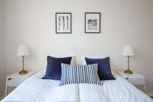 un letto bianco con cuscini blu e 2 lampade; di 2ndhomes Fabianinkatu Apartment a Helsinki