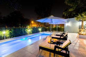 a swimming pool with two chairs and an umbrella at Top View Hotel - SHA Extra Plus in Si Racha
