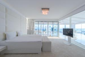 a white bedroom with a bed and a television at Grand Hotel Sveti Vlas-Ultra All Inclusive Fitness & SPA Hotel in Sveti Vlas