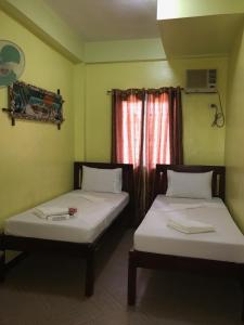 two beds in a room with a window at Luis Bay Travellers Lodge in Coron