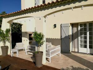 a patio with white chairs and a sliding door at Bastide Philomen in Pérols