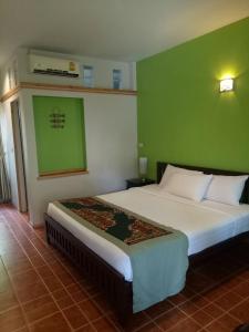 a bedroom with a bed and a green wall at Baan Jaru in Chiang Rai