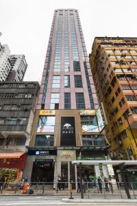 Un grand bâtiment avec des gens qui marchent devant lui dans l'établissement Eco Tree Hotel, à Hong Kong