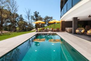 una piscina con sillas y sombrillas junto a un edificio en LAVIDA Hotel at Camiral Golf & Wellness en Caldes de Malavella