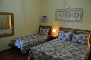 a bedroom with two beds and a mirror at Pousada Berço da Liberdade in Tiradentes
