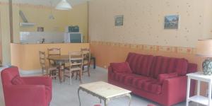 Una sala de estar con un sofá rojo y una mesa. en appartement au gagne petit 25 kilomètres du parc le pal, en Bourbon-Lancy
