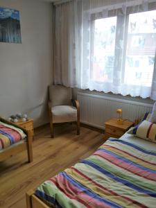イェレニャ・グラにあるApartament pod Strzelecką Górąのベッドルーム1室(ベッド2台、椅子、窓付)