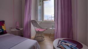 1 dormitorio con silla y ventana con cortinas moradas en Apartments & Rooms Josephine, en Senj