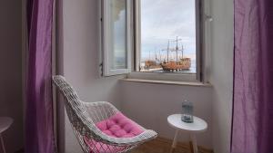 una silla con un cojín rosa sentada junto a una ventana en Apartments & Rooms Josephine en Senj