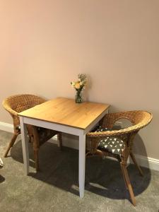 a table with two chairs and a vase of flowers on it at Mays Cottage Bed and Breakfast in Petersfield