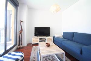 a living room with a blue couch and a tv at CasaTuris Playa, piscina y parking en Residencial San Juan SJ102 in Alicante