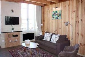 a living room with a couch and a tv at Le Latour, Centre-ville - Parking Gratuit in Bordeaux