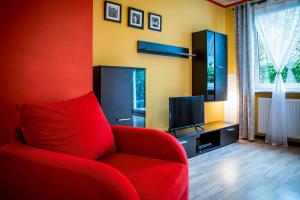 ポズナンにあるDarna Apartamenty Avena 1のリビングルーム(赤いソファ、テレビ付)