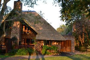 ヘイジービューにあるKruger Park Lodge - Golf Safari SAの茅葺き屋根の古いレンガ造りの家