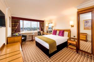 una camera d'albergo con un letto e una grande finestra di Copthorne Tara Hotel London Kensington a Londra