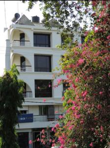 a white building with windows and pink flowers at Balcony Rooms Overlooking the Main Market in Pachmarhī