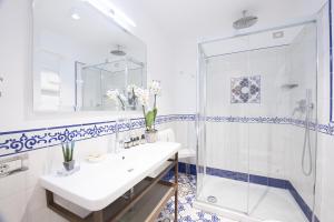 a white bathroom with a shower and a sink at DieciSedici in Amalfi