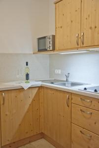 uma cozinha com armários de madeira, um lavatório e uma garrafa de vinho em Landhaus Essl em Dietach