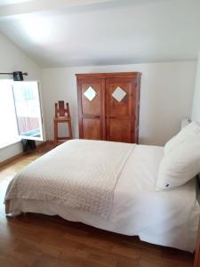 1 dormitorio con cama blanca y armario de madera en gite du montagnard en Oxelaere