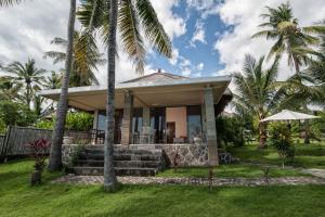 una casa con palmeras delante en Relax Bali Dive & SPA ocean front resort, en Tulamben