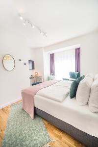 a white bedroom with a large bed and a rug at Victoria Hotel in Düsseldorf