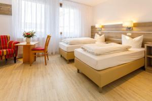 Habitación de hotel con 2 camas, mesa y silla en Hotel Spitzenpfeil en Michelau