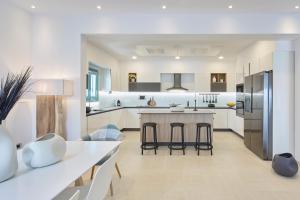a kitchen with white cabinets and a kitchen island with bar stools at Almyriki Beach Villa in Monolithos