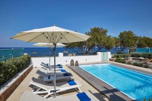 una piscina con tumbonas, una sombrilla y una piscina en Almyriki Beach Villa, en Monolithos