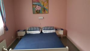 a small bedroom with a blue bed with two pillows at Milas House two apartments in Fredvang