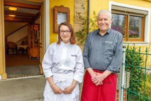 Ein Mann und eine Frau stehen vor einem Haus in der Unterkunft Hotel Spitzenpfeil in Michelau