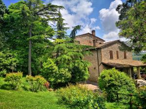 una vecchia casa di mattoni circondata da alberi e cespugli di Agriturismo Casale Dei Frontini a San Terenziano