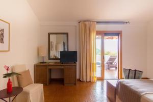 a living room with a bed and a television at Hotel Aquadulci in Chia