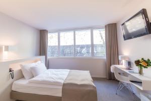 una camera d'albergo con letto, scrivania e TV di Hotel Lavaux a Cully