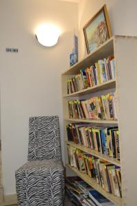 a book shelf filled with books next to a chair at Hotel Diamanti in Sozopol