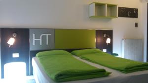 Un dormitorio con una cama con almohadas verdes. en Hotel Toresela Bike am Gardasee, en Nago-Torbole