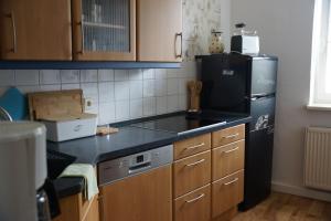 eine Küche mit einem schwarzen Kühlschrank und Holzschränken in der Unterkunft Ferienwohnung Regina in Mühlhausen