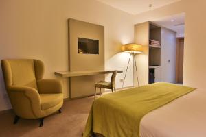 ein Hotelzimmer mit einem Bett, einem Stuhl und einem Schreibtisch in der Unterkunft Delfim Douro Hotel in Lamego