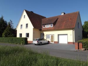 ein weißes Haus mit einem Auto in der Einfahrt in der Unterkunft Gute Nacht Ferienwohnung in Halle Westfalen
