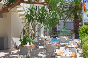 un restaurante con mesas, sillas y palmeras en Olympic Palladium, en Rethymno