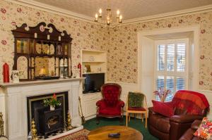a living room with a fireplace and red chairs at Harbour House B&B in Courtown