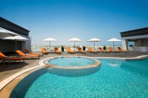 a swimming pool with chairs and umbrellas on a building at Fraser Suites Muscat in Muscat