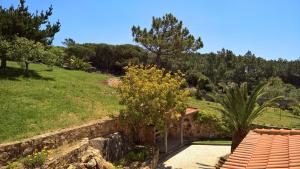 a garden with a stone wall and trees at Quinta do Cabo Guesthouse in Sintra
