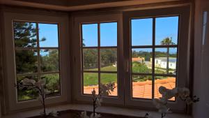 a room with three windows with a view of a roof at Quinta do Cabo Guesthouse in Sintra